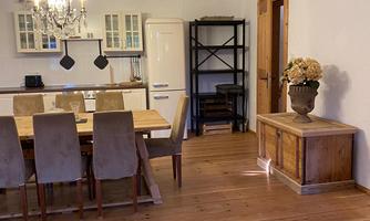 A cozy dining area with a long wooden table and chairs. The room has wooden floors and modern lighting.