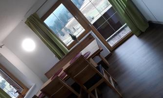 A bright dining room with a wooden table and chairs. Large windows offer a view of the landscape.