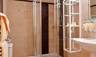 A modern bathroom with a round shower and a sink. The walls are light and the fixtures are functional.
