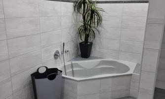 A modern bathroom with a bathtub and a green plant. The bright tiles create a friendly atmosphere.