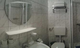 A small bathroom with modern fixtures. There is a shower, a sink, and a mirror on the wall.