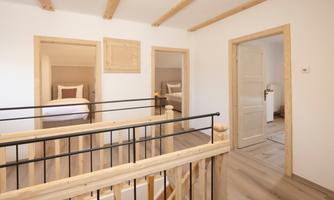 A bright hallway with a wooden staircase and modern rooms. The walls are painted in neutral colors and the atmosphere feels inviting.