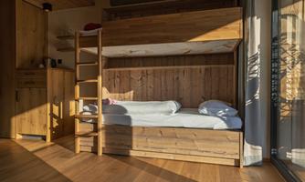 A bright room with a wooden bunk bed. The warm wood surfaces create a cozy atmosphere.