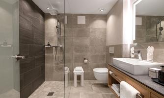 A modern bathroom with a glass shower and elegant tiles. The vanity is made of wood and provides plenty of storage space.