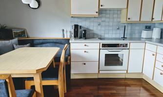 A bright kitchen with modern design and a dining area. The furniture is made of wood and there is a cooking facility with appealing appliances.