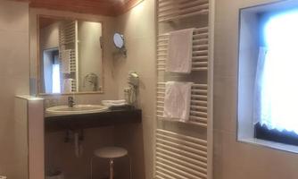 A modern bathroom with an elegant sink and a large mirror. There is also a towel radiator and plenty of natural light from a window.