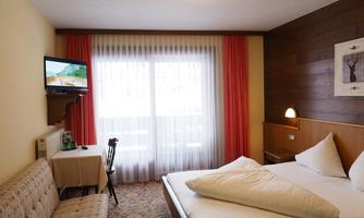 A cozy hotel room with a double bed and a television. Large windows provide plenty of natural light.