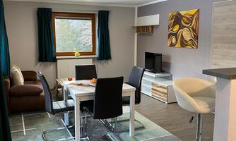 A modern living room with a dining area and a cozy sofa. Large windows provide plenty of daylight and an inviting atmosphere.