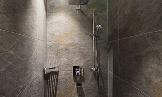 A modern shower with gray tiles and elegant fixtures. The rain shower provides a luxurious shower experience.