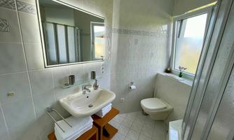 A modern bathroom with a sink, a mirror, and a shower. The bright tiles and natural light create a friendly atmosphere.