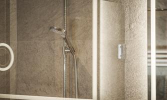 A modern bathroom with a glass shower cabin. The walls are in neutral tones and softly illuminated.