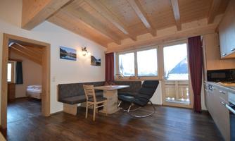 A cozy apartment with a wooden ceiling and a dining area. Large window with a view of the mountains.