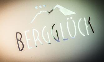 A simple logo with the inscription "Bergglück". In the background, stylized mountain shapes and stars are visible.