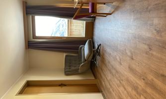 A cozy room with an armchair and a desk. The window offers a view of the mountains.