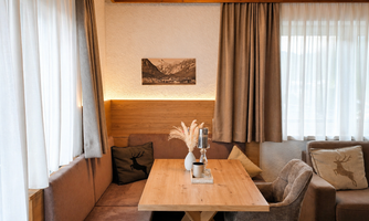 A cozy dining area with a wooden table and comfortable seating.  
Large windows let in plenty of light, creating an inviting atmosphere.