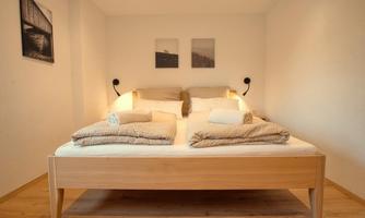 A cozy bedroom with a large double bed and simple, modern furnishings. Soft colors and subtle lighting create a relaxing atmosphere.