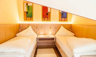 A cozy room with two single beds and modern wood paneling. Colorful wall art provides an inviting accent.