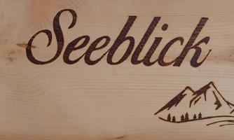 A wooden sign with the inscription "Seeblick" and a simple mountain graphic. It conveys a sense of nature and tranquility.