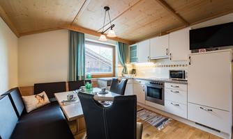 A modern kitchen with a dining table and cozy seating. Bright walls and wooden details create an inviting atmosphere.