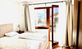A cozy bedroom with a double bed and white walls.  <br/>Large windows let in plenty of daylight and offer a view of the mountains.