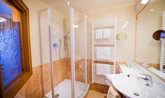 A modern bathroom with a glass shower and elegant tiles. Towels are neatly hung, and the space feels bright and inviting.