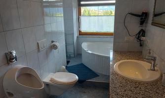 A modern bathroom with a bathtub, sink, and a toilet. Bright tiles and a window provide plenty of daylight.