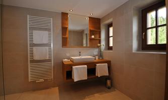 A modern bathroom with elegant sanitary fittings. It features a vanity, large mirrors, and warm wood accents.