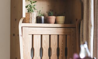 A wooden shelf with various pots and plants. In the foreground, a table with a glass bottle is visible.