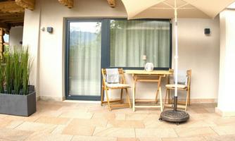 A cozy terrace with a table and two chairs. A parasol and plants create a pleasant atmosphere.