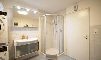 A modern bathroom with a shower cubicle and a sink. Bright colors and a practical arrangement of the furniture create an inviting atmosphere.
