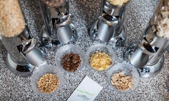 A selection of muesli varieties in glass containers and small bowls. Beneath it lies a card with the inscription "Kitchen Bar".