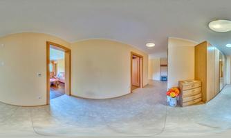 A bright hallway with neutral walls and carpet flooring. In the background, several doors and a dressing closet are visible.