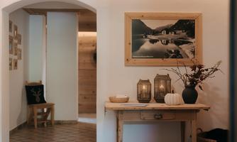 A cozy entryway with a wooden desk and decorative elements. On the wall hangs a picture of an idyllic landscape with a lake.