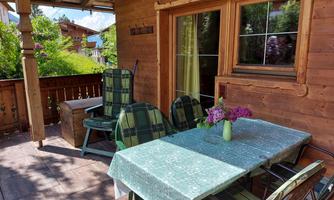 A cozy terrace with a table and chairs. On the table is a vase with fresh flowers.