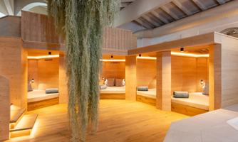 A modern wellness area with comfortable wooden relaxation platforms. Gentle lighting and decorative greenery create a relaxing atmosphere.