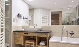 A modern bathroom with an elegant shower, a bathtub, and a wooden vanity. The walls are bright and reflect light well.