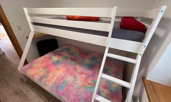 A loft bed with a colorful, fluffy blanket. The lower bed is cozy equipped with pillows and blankets.