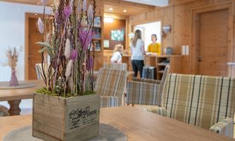 A cozy interior with a wooden log and dried flowers as decoration. In the background, people can be seen at a reception counter.
