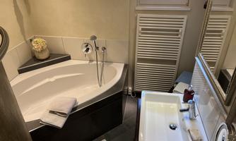A modern bathroom with an elegant bathtub and a sink. The design is bright and inviting, with beautiful home decor.