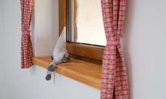 A small decorative figure sits on the windowsill. Red curtains frame the window.