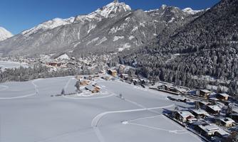 A picturesque winter landscape with snow-covered mountains and a tranquil village. The houses are nestled in the white splendor of nature.