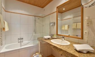 A modern bathroom with a bathtub and a shower. The granite vanity is decorated with towels and toiletries.