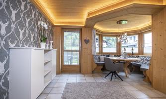 A cozy living space with a wooden ceiling and modern furniture. Large windows provide a view of the surroundings and ensure plenty of daylight.