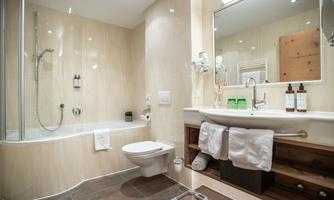 A modern bathroom with a bathtub and a shower. The decor is bright and inviting, with toiletries and fresh towels.