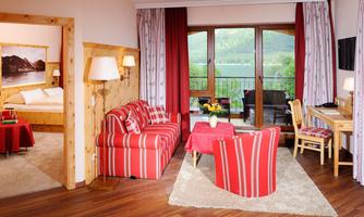 A cozy living room with red striped furniture and a view of the mountains through large windows. The room is bright and well-decorated, ideal for relaxation.
