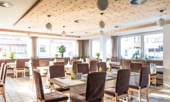 A modern restaurant with bright, spacious tables and chairs. Large windows let in plenty of daylight and create a pleasant atmosphere.