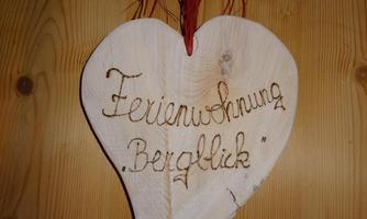 A wooden heart-shaped sign with the inscription "Vacation Apartment Mountain View". It hangs on a wooden wall.