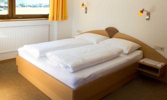 A cozy bedroom with a double bed and bright curtains. The room has a window that lets in daylight.
