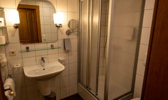 A modern bathroom with a shower cabin and a sink. The walls are tiled and the lighting is pleasant.