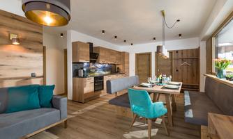 A modern kitchen with wooden cabinets and a cozy dining area. The room is bright and inviting, with stylish furniture and a warm atmosphere.